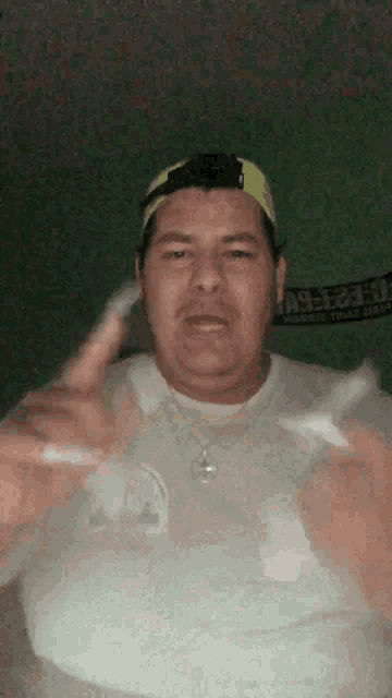 a man wearing a white shirt and a yellow hat is giving a peace sign
