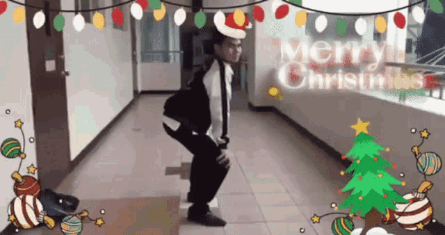 a man wearing a santa hat is squatting down in a hallway with merry christmas written in the background