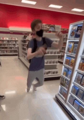 a man wearing a mask is running through a store aisle
