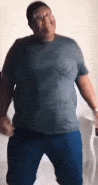 a man wearing a gray shirt and blue pants is dancing .