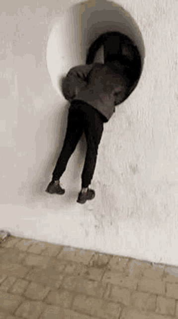 a person is crawling through a hole in a white wall .