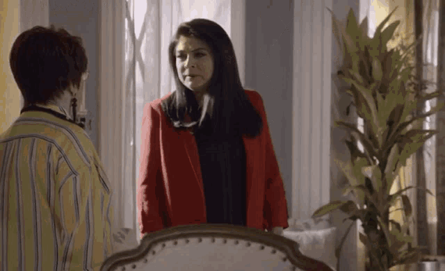 a woman in a red jacket is standing next to another woman in a yellow shirt