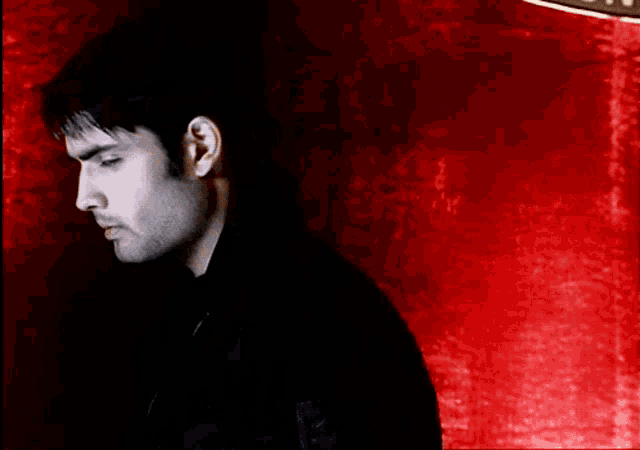 a man is standing in front of a red curtain