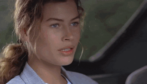a close up of a woman 's face with a ponytail in a car