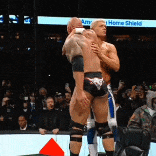 two men are wrestling on a stage with a sign that says home shield