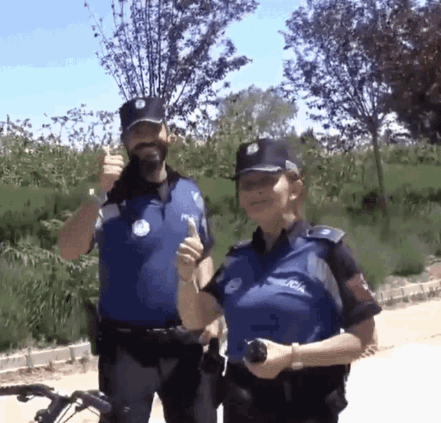 two police officers giving a thumbs up in front of a bicycle