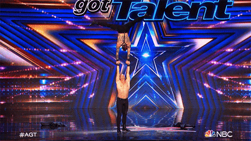 a man is holding another man up in the air on a stage with a star in the background .