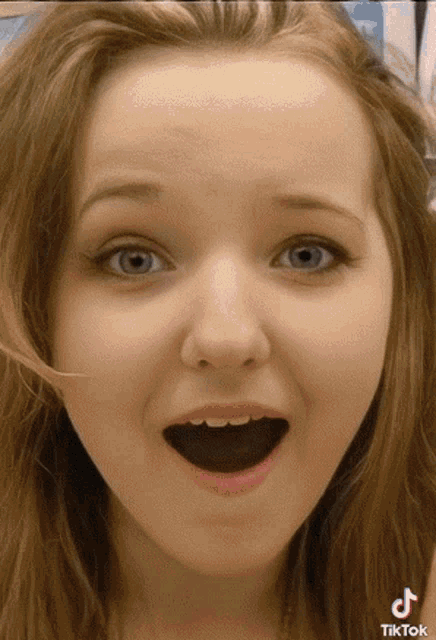 a close up of a girl 's face with a tiktok logo on the bottom right