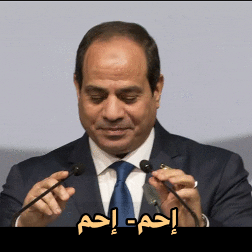 a man in a suit and tie is holding a microphone with arabic writing on it