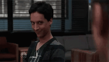 a man in a scrub top is making a funny face while sitting in a waiting room .