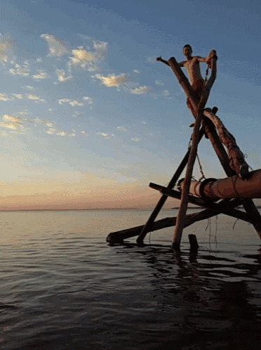 a man is standing on a wooden structure in the water