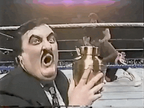 a man in a suit and tie is holding a trophy with his mouth open .