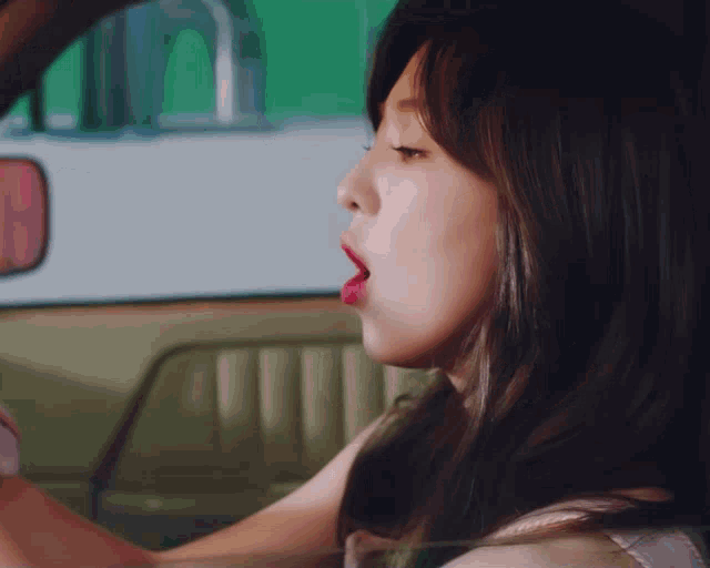 a woman driving a car with her mouth open and her tongue out