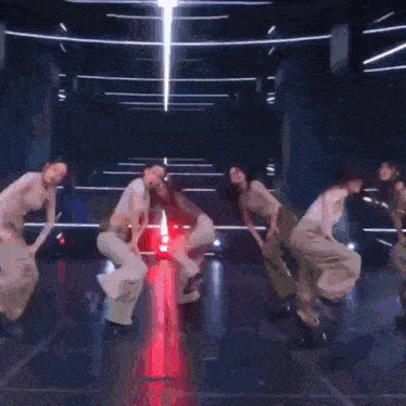 a group of people are dancing together on a stage in a dark room .
