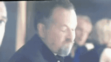 a man with a beard is standing in front of a group of people in a room .