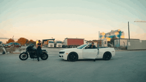 a man on a motorcycle next to a white car
