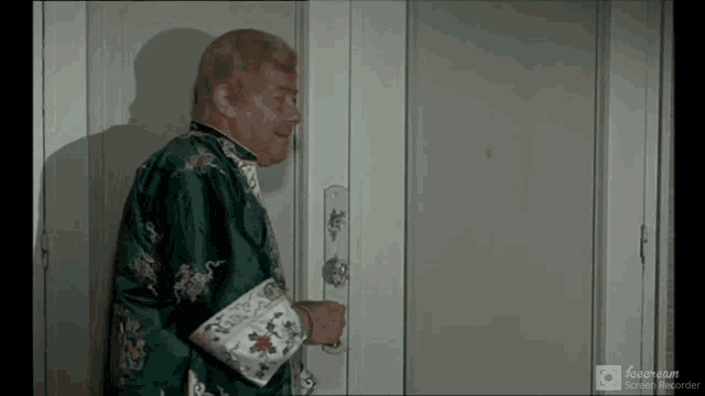 a man in a green robe is standing in front of a white door
