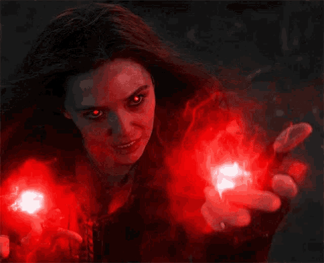 scarlet witch is holding a red light in her hands .