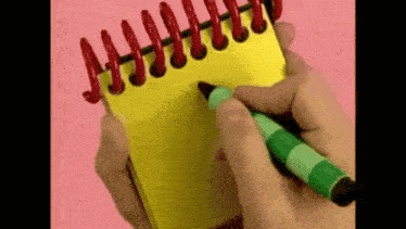 a person is writing in a notebook with a green marker