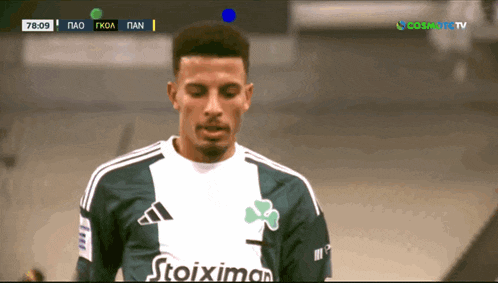 a soccer player wearing a stoixima jersey looks down