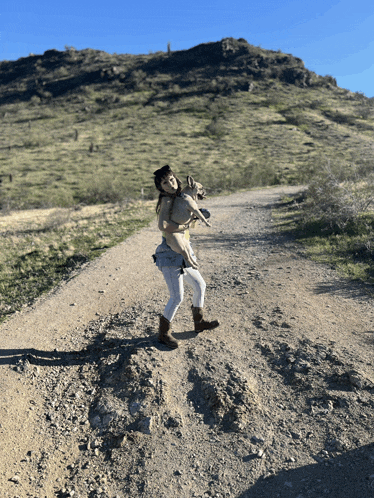 a woman holds a dog on a dirt road