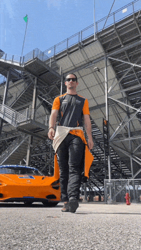 a man walking in front of a race car that says ' mclaren ' on it