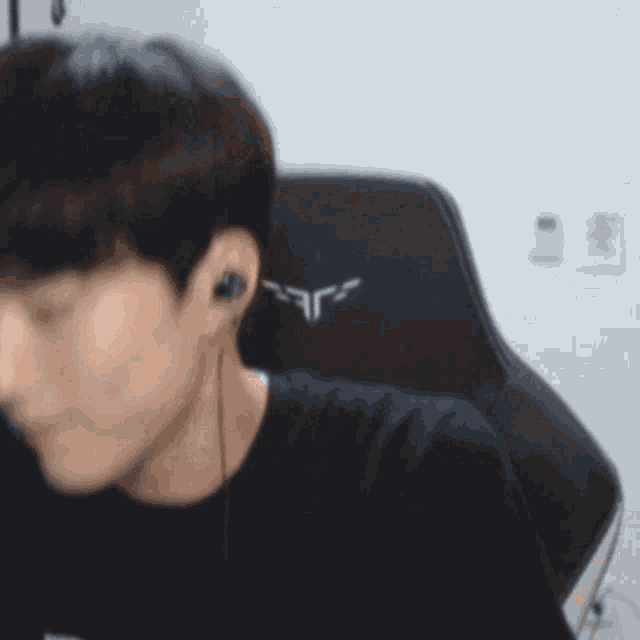 a man wearing headphones and a black shirt is sitting in a gaming chair .