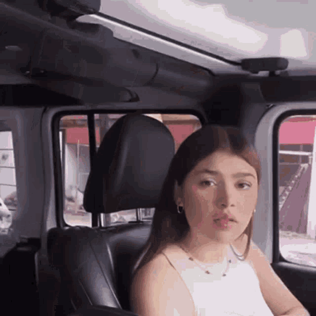 a woman is sitting in the back seat of a car looking at the camera