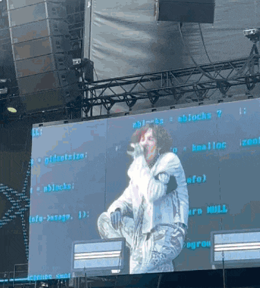 a man singing into a microphone in front of a large screen that says " blocks "