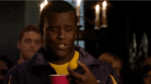 a man in a purple jacket is holding a pink cup and asking " gay much "
