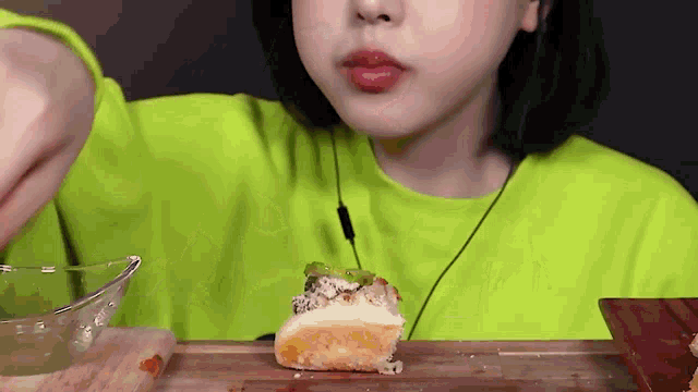 a woman in a neon green shirt is eating a piece of bread