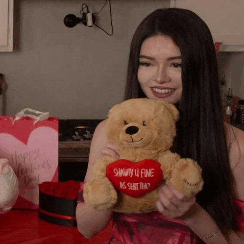 a woman holds a teddy bear with a heart that says shawty u fine is shit tho