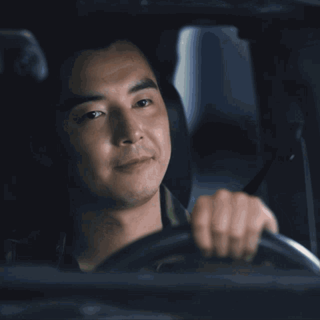 a man driving a car with chinese writing on the bottom