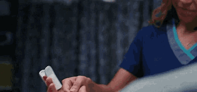 a nurse is holding a pulse oximeter in a patient 's hand in a hospital room .