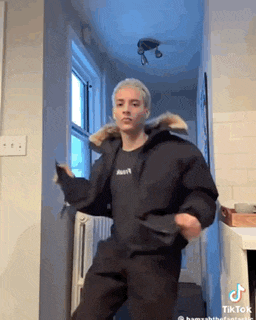 a man in a black jacket is dancing in a hallway in a room .