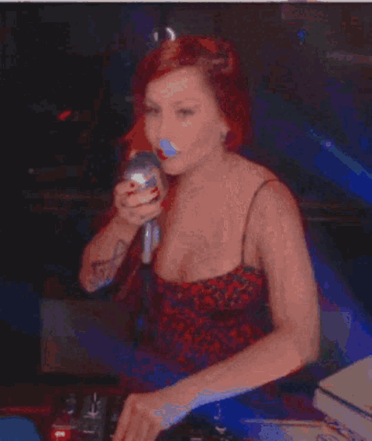 a woman with red hair is wearing ear buds and a red top