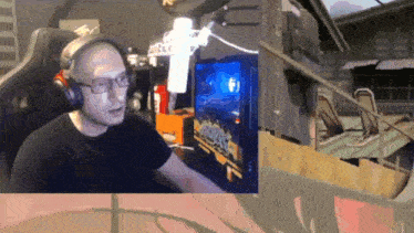 a man wearing headphones and glasses is playing a video game in front of a microphone that says ' riot '