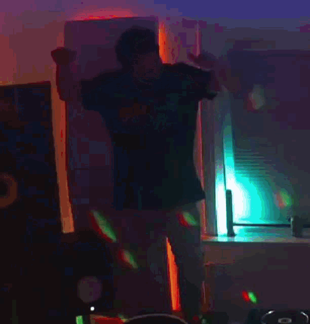 a man is dancing in a dark room with a disco ball behind him .