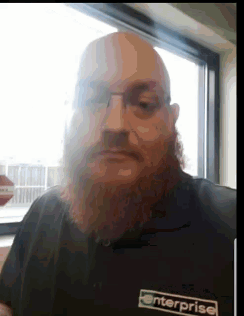 a bald man with a beard is wearing glasses and a shirt that says enterprise on it