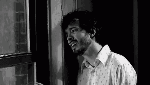 a man with a beard is standing in front of a window .