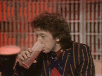 a man in a striped jacket is drinking from a plastic cup .