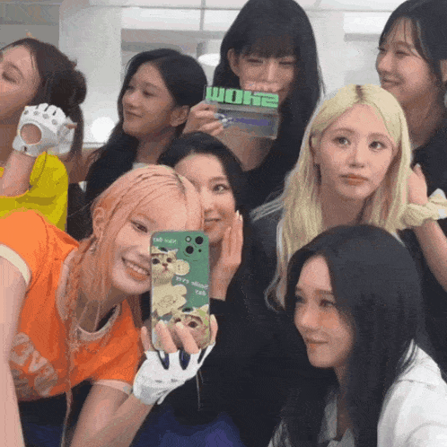 a group of girls are posing for a picture and one girl is holding a phone case that says ' wome '