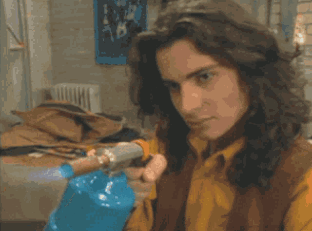 a man with long hair is holding a blue bottle in his hands