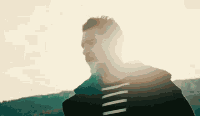 a man in a black hoodie with white stripes on the sleeves