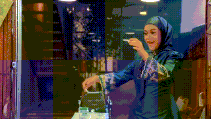 a woman in a hijab is standing in front of a screen door holding a cigarette .