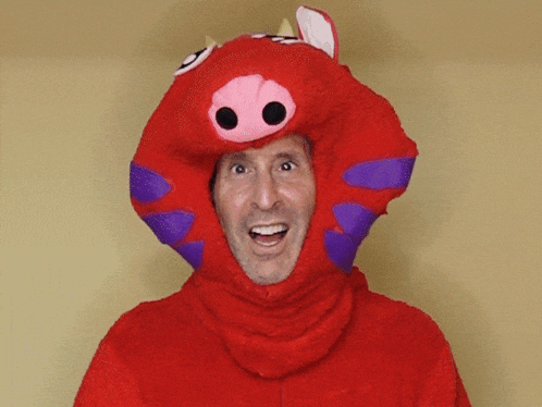 a man in a red pig costume is smiling and pointing