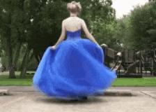 a woman in a blue dress is spinning in a park .