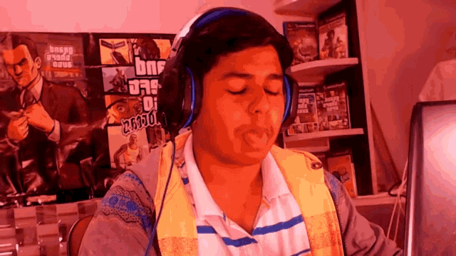 a young man wearing headphones with a grand theft auto poster behind him