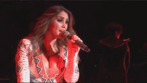 a woman is singing into a microphone in a dark room .