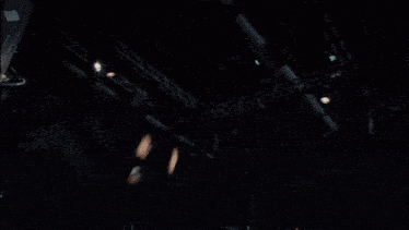 a group of people are gathered in a dark room with a statue in the background